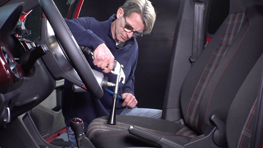 En person rengjør forseteret i en bil med en Tornador TORNADOR® BLACK Z-020RS.