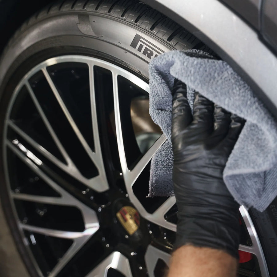 En hånd i hanske tørker av et bildekk med TPG Quattro, der Pirelli-logoen er synlig på felgen.