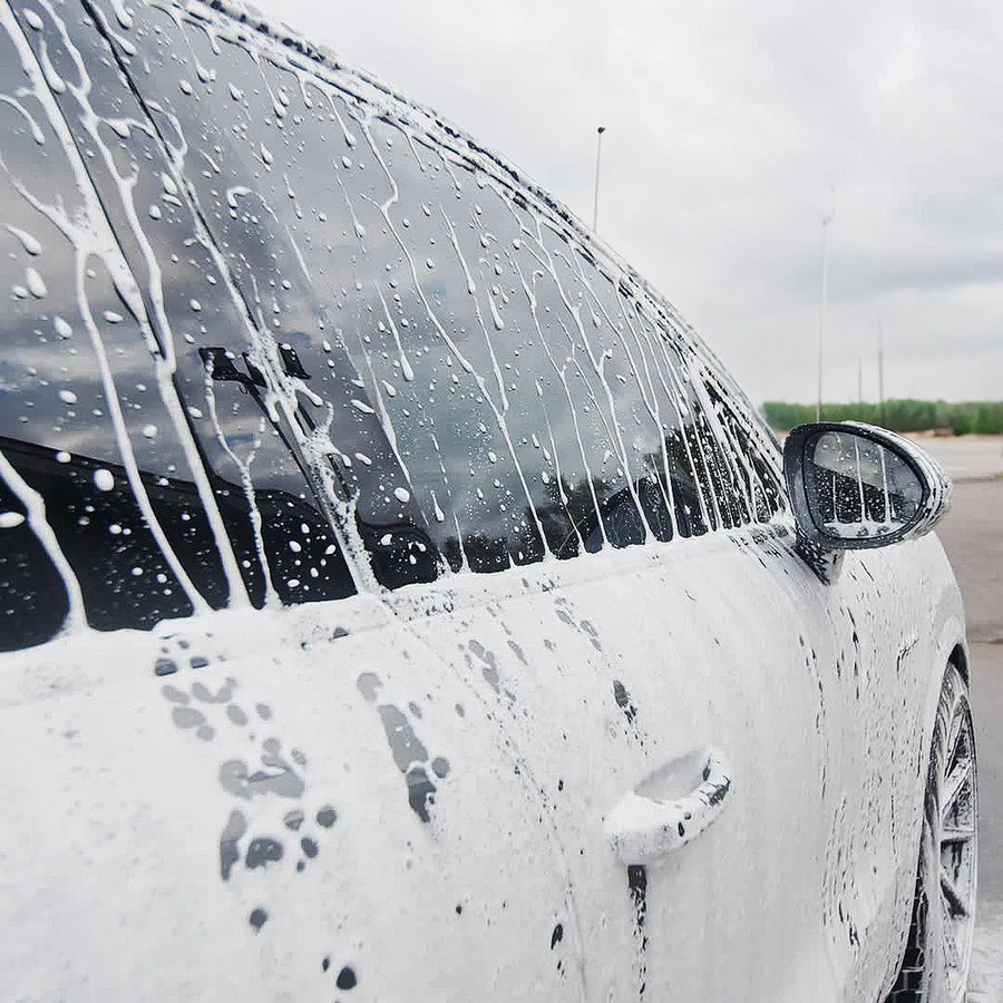 En hvit bil vaskes utendørs med The Perfect Gloss TPG Ultra Leggera Quickdetailer & Wetcoat (500 ml) på en overskyet dag.
