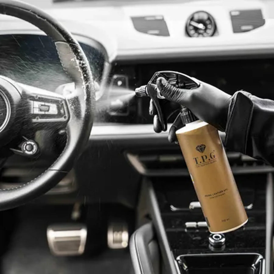 En hånd i hanske sprayer «The Perfect Gloss TPG Piuma Leather APC» på et moderne bilratt.